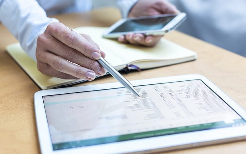 Homme sur tablette devant un document excell